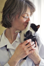 Dr. Nicoleta Popescu with a tiny black and white kitty who puts his paw on her nose.